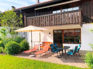 a patio with a table and chairs and an umbrella at Ferienwohnung Enzian 1 im Feriendorf Sonnenhang im Allgäu in Missen-Wilhams