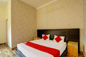 um quarto com uma cama grande e almofadas vermelhas em OYO Flagship Hotel Jagdambey Residency em Noida