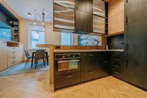 una cocina con armarios de madera y una mesa con una silla en Krupówki 25A Górski Loft by Homeprime, en Zakopane