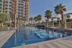 duży basen z palmami i budynek w obiekcie Luxury living near Dubai Expo - Dubai South - Ezytrac Vacation Homes w Dubaju
