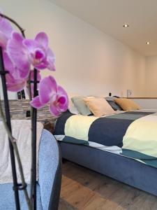 een slaapkamer met een bed en een paarse bloem op een stoel bij AMIKALEMENT VÔTRE - Gîte 2 personnes in La-Roche-en-Ardenne