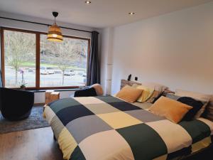 een slaapkamer met een bed en een groot raam bij AMIKALEMENT VÔTRE - Gîte 2 personnes in La-Roche-en-Ardenne