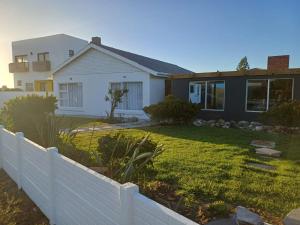 a house with a white fence in front of a yard at Versveld Cottage in Yzerfontein