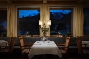 comedor con mesa, sillas y ventanas en Arabella Alpenhotel am Spitzingsee, a Tribute Portfolio Hotel en Spitzingsee