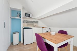 een keuken met een houten tafel en paarse stoelen bij Appartement budget avec parking au centre-ville in Charleville-Mézières
