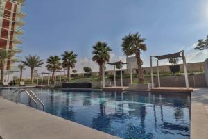 a swimming pool with palm trees and a building at Affordable Living near Dubai Al Makhtom Airport - Ezytrac Vacation Homes in Dubai