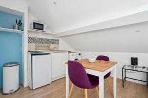 een kleine keuken met een houten tafel en paarse stoelen bij Appartement budget avec parking au centre-ville in Charleville-Mézières