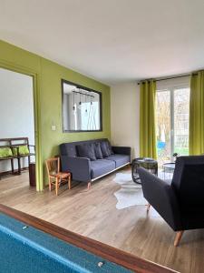 a living room with a blue couch and green walls at Le Bleu de B. in Saint-Étienne-en-Bresse