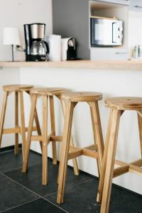 a kitchen counter with three wooden stools and a microwave at Le Gîtel in Spa