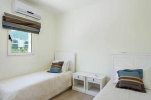 a white room with two beds and a window at Joya Cyprus Mandalay Penthouse Apartment in Saint Amvrosios +20 photos