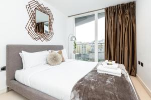 a bedroom with a bed and a large window at Stylish Central 2BR Flat, Belgravia, Chelsea in London