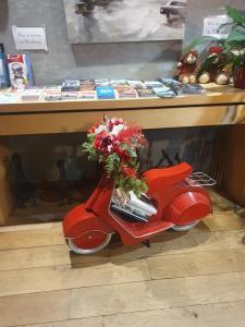 a red scooter with a bouquet of flowers sitting under a table at EtC...Hôtel - Strasbourg Hyper Centre in Strasbourg