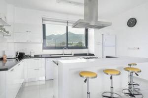 a white kitchen with white cabinets and yellow bar stools at Joya Cypern Seaside Luxurious Villa and Private Pool in Akanthou