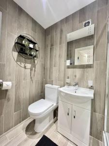 La salle de bains est pourvue de toilettes blanches et d'un lavabo. dans l'établissement City Centre Apartments for Large Groups - Superb Location & Next to Tube Station, à Ealing