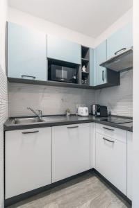 La cuisine est équipée de placards blancs, d'un évier et d'un four micro-ondes. dans l'établissement Castle Charm Apartment/ AC, à Budapest