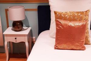 ein Bett mit einem Kissen und einer Lampe auf einem Beistelltisch in der Unterkunft ROYAL SUITE PARIS REPUBLIQUE in Paris