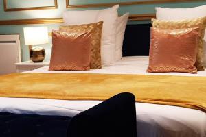 - une chambre dotée d'un grand lit avec des oreillers bruns et blancs dans l'établissement ROYAL SUITE PARIS REPUBLIQUE, à Paris