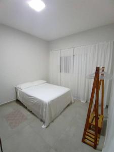 a white bedroom with a bed and a glass table at Casa com Piscina e ótimo custo benefício!! in Brotas