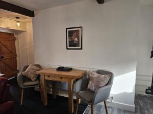 Habitación con mesa de madera y 2 sillas. en Hop Cottage en Mirfield