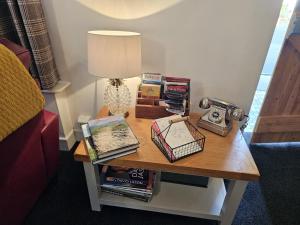 una mesa con una lámpara y libros en ella en Hop Cottage en Mirfield