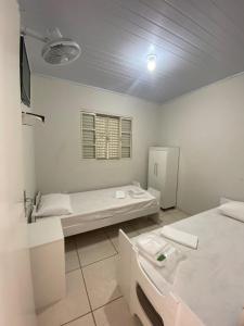 Cette chambre blanche comprend un lit et un lavabo. dans l'établissement POUSADA OASIS DE MINAS, à Carmo do Rio Claro