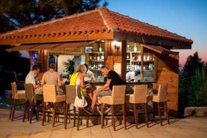 un grupo de personas sentadas en un bar en Joya Cyprus Sugarberry Garden Apartment, en Saint Amvrosios