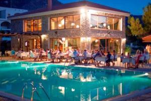 a group of people sitting around a pool in front of a building at Joya Cyprus Sugarberry Garden Apartment in Saint Amvrosios