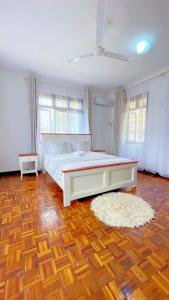 a bedroom with a large bed and a wooden floor at Villa Ella in Mombasa
