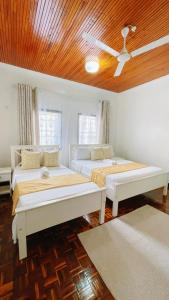 two beds in a room with a wooden ceiling at Villa Ella in Mombasa