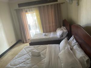 a bedroom with two beds and a window at 7 Days Hotel in Entebbe