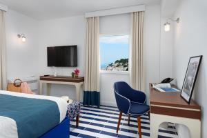 a hotel room with a bed and a desk and a window at Villa Lia Hotel Capri in Capri