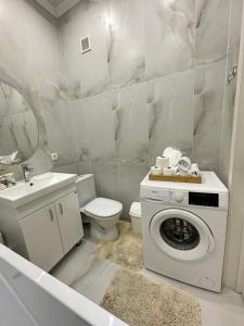 uma casa de banho com uma máquina de lavar roupa e um WC em Абсолютно новая евродвушка в ЖК Комфортсити em Almaty
