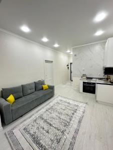 uma sala de estar com um sofá e uma cozinha em Абсолютно новая евродвушка в ЖК Комфортсити em Almaty