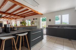 a large kitchen with black counter tops and stools at LE GARCIA villa au calme et vue sur les montagnes in Urrugne