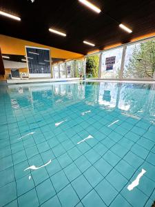 - une grande piscine revêtue de carrelage bleu dans l'établissement Hotel Lindenhof by Crossworld AG, à Brienz