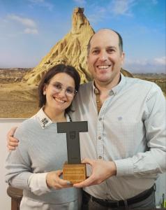 Un uomo e una donna con una targa con una croce di Horno de la Higuera Alojamiento a Tudela