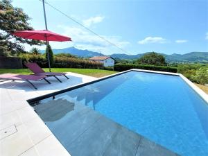 een zwembad met een rode parasol en een stoel bij LE GARCIA villa au calme et vue sur les montagnes in Urrugne