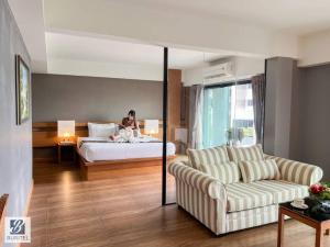 a woman sitting on a bed in a hotel room at Buritel Hotel in Buriram