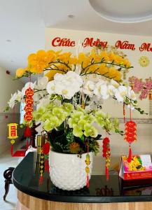 un jarrón lleno de flores amarillas y blancas en una mesa en Phương Thảo Motel (phòng đơn), en Vung Tau