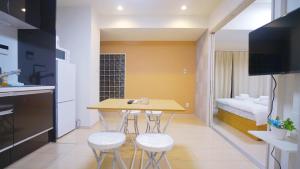 a small kitchen with a table and stools and a bed at TOKYO SHINJUKU MIO HOTEL in Tokyo