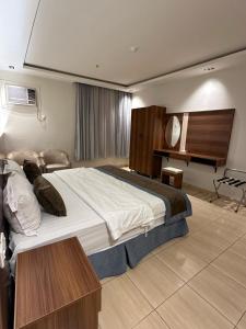 a bedroom with a large bed and a desk at Dosh Hotel in Al Madinah