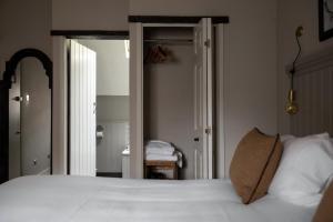 a bedroom with a white bed and a mirror at The White Hart Ford in Ford