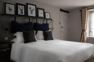 a bedroom with a large white bed with black pillows at The White Hart Ford in Ford