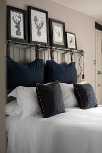 a bed with black and white pillows and framed pictures at The White Hart Ford in Ford