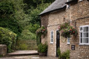 an old stone house with flowers on the door at The White Hart Ford in Ford +13 photos