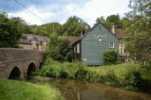 a blue house next to a river with a bridge at The White Hart Ford in Ford