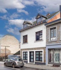 een auto geparkeerd voor een wit huis bij Le Quatre F in La-Roche-en-Ardenne