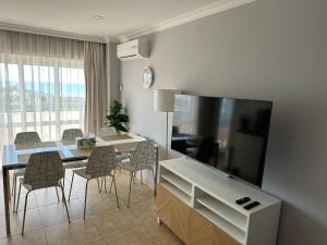 uma sala de estar com uma mesa de jantar e uma grande televisão em Brisa Atlântica em Portimão