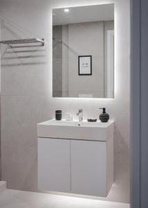 W białej łazience znajduje się umywalka i lustro. w obiekcie Syntagma Unique Penthouse w Atenach