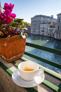 una taza de café sentada en una mesa junto a una flor en Ca Zulian Venice - Grand Canal, en Venecia